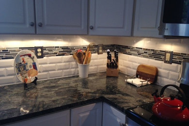 Mid-sized elegant l-shaped enclosed kitchen photo in New York with raised-panel cabinets, gray cabinets, marble countertops, multicolored backsplash, ceramic backsplash, stainless steel appliances and no island