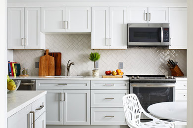 Eat-in kitchen - mid-sized traditional vinyl floor eat-in kitchen idea in DC Metro with white cabinets, white backsplash, subway tile backsplash and stainless steel appliances