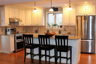 Inspiration for a mid-sized timeless l-shaped medium tone wood floor and brown floor kitchen remodel in Phoenix with raised-panel cabinets, white cabinets, granite countertops, beige backsplash, stone tile backsplash, stainless steel appliances and an island