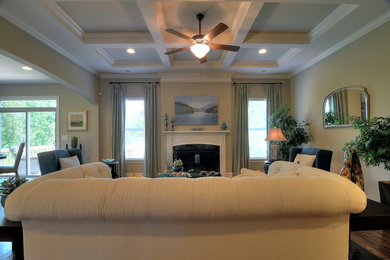 Example of a trendy medium tone wood floor family room design in Charlotte with beige walls and a standard fireplace