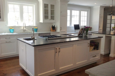 Example of a large transitional l-shaped medium tone wood floor open concept kitchen design in New York with an undermount sink, recessed-panel cabinets, white cabinets, marble countertops, white backsplash, ceramic backsplash, stainless steel appliances and two islands