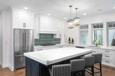 Photo of a mid-sized transitional kitchen in Other with a single-bowl sink, white cabinets, green splashback, ceramic splashback, stainless steel appliances, laminate floors, with island and white benchtop.