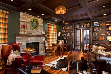 Elegant medium tone wood floor and brown floor family room photo in Boston with green walls, a standard fireplace and a stone fireplace