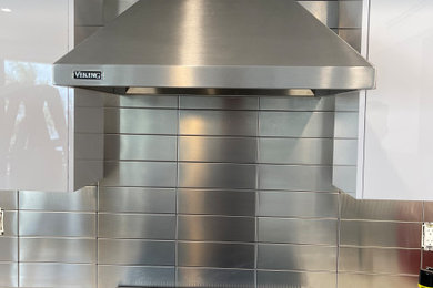 Kitchen - modern kitchen idea in Miami with white cabinets, metallic backsplash, metal backsplash and white countertops