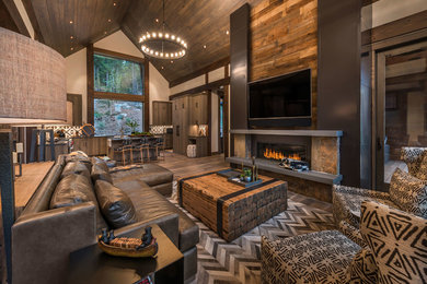 Ejemplo de sala de estar abierta rural grande con paredes multicolor, suelo de madera oscura, televisor colgado en la pared y suelo marrón