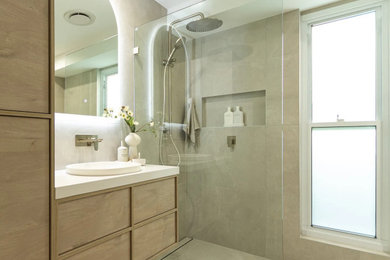 Photo of a large modern kids bathroom in Sydney with beaded inset cabinets, light wood cabinets, a corner tub, an open shower, gray tile, a drop-in sink, grey floor, an open shower, white benchtops, a niche, a single vanity and a floating vanity.