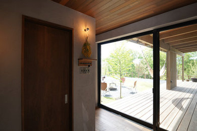 他の地域にある広いインダストリアルスタイルのおしゃれな玄関 (グレーの壁、濃色木目調のドア、グレーの床、板張り天井) の写真