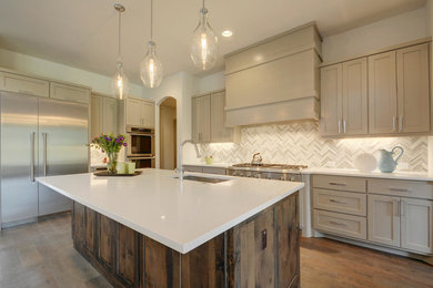 Large trendy l-shaped light wood floor open concept kitchen photo in Austin with an undermount sink, shaker cabinets, gray cabinets, quartz countertops, white backsplash, mosaic tile backsplash, stainless steel appliances and an island