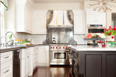Inspiration for a large transitional u-shaped dark wood floor and brown floor enclosed kitchen remodel in San Francisco with an undermount sink, recessed-panel cabinets, white cabinets, granite countertops, white backsplash, stone tile backsplash, stainless steel appliances and an island