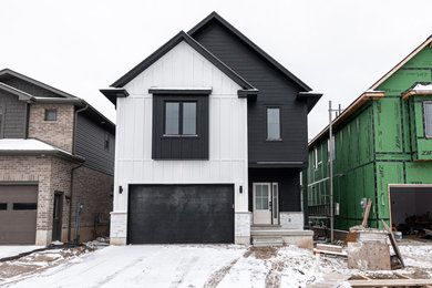 Example of a mid-sized transitional black two-story concrete fiberboard and board and batten exterior home design in Toronto with a shingle roof and a black roof