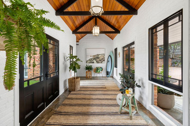 Inspiration for a large country foyer in Geelong with white walls, slate floors, a double front door, a black front door, exposed beam and brick walls.