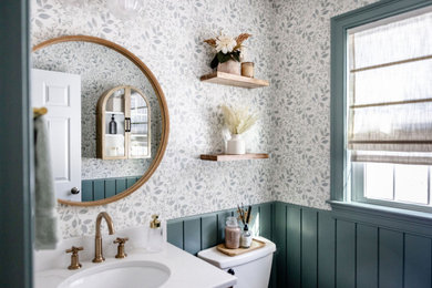 Example of a mid-sized cottage ceramic tile, brown floor and wallpaper powder room design in Boston with shaker cabinets, medium tone wood cabinets, a drop-in sink, quartzite countertops, white countertops and a freestanding vanity