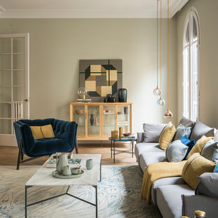 Modelo de salón para visitas cerrado, mediterráneo, grande, sin televisor, con paredes beige, suelo de madera en tonos medios, marco de chimenea de yeso y suelo beige