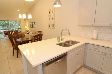 Inspiration for a small transitional galley ceramic tile and gray floor open concept kitchen remodel in Orlando with an undermount sink, shaker cabinets, gray cabinets, quartz countertops, white backsplash, ceramic backsplash, stainless steel appliances, a peninsula and gray countertops
