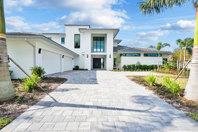 Inspiration for a large modern white two-story stucco house exterior remodel in Miami with a hip roof and a shingle roof