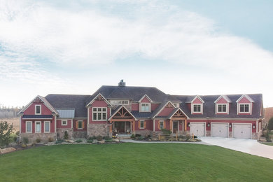 This is an example of an expansive country two-storey red house exterior in Cleveland with vinyl siding, a gable roof and a shingle roof.