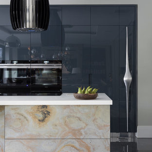 Large contemporary kitchen pantry inspiration - Example of a large trendy galley porcelain floor and gray floor kitchen pantry design in Hertfordshire with an undermount sink, flat-panel cabinets, distressed cabinets, quartzite countertops, black appliances, an island and white countertops