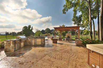 Large minimalist backyard stamped concrete patio kitchen photo in Philadelphia with a pergola