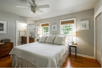 Example of a mid-sized transitional master medium tone wood floor and brown floor bedroom design in New Orleans with gray walls and no fireplace