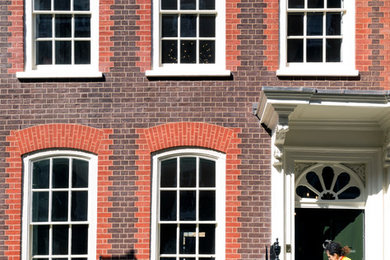 Red and medium sized contemporary brick terraced house in London with three floors, a pitched roof and a tiled roof.