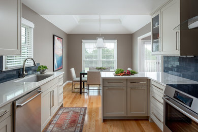 Inspiration for a mid-sized contemporary galley medium tone wood floor enclosed kitchen remodel in Louisville with an undermount sink, recessed-panel cabinets, white cabinets, quartz countertops, blue backsplash, ceramic backsplash, stainless steel appliances, a peninsula and white countertops
