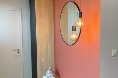 Aménagement d'un hall d'entrée éclectique avec un mur orange et parquet foncé.