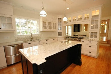 Large farmhouse u-shaped medium tone wood floor eat-in kitchen photo in Boston with an undermount sink, shaker cabinets, white cabinets, marble countertops, white backsplash, stone slab backsplash, stainless steel appliances and an island