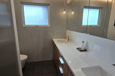Example of a small mid-century modern master gray tile and porcelain tile porcelain tile, black floor and double-sink walk-in shower design in Ottawa with flat-panel cabinets, medium tone wood cabinets, a wall-mount toilet, white walls, an undermount sink, quartz countertops, a hinged shower door, white countertops, a niche and a built-in vanity