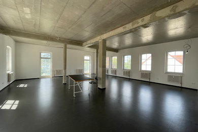 ベルリンにある低価格の中くらいなモダンスタイルのおしゃれなリビング (白い壁、リノリウムの床、暖炉なし、テレビなし、黒い床) の写真