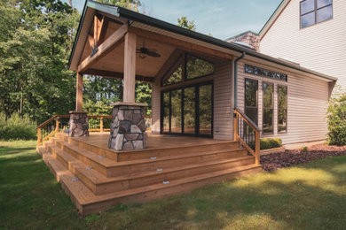 Transitional backyard ground level privacy and mixed material railing deck photo in Cleveland with a roof extension
