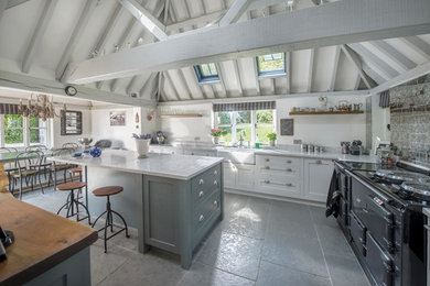 Mid-sized country l-shaped slate floor enclosed kitchen photo in Other with a farmhouse sink, shaker cabinets, white cabinets, marble countertops, metallic backsplash, mirror backsplash and an island