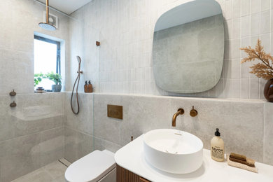 This is an example of a mid-sized contemporary 3/4 bathroom in Sydney with an open shower, a one-piece toilet, gray tile, a vessel sink, grey floor, an open shower, white benchtops, a single vanity and a floating vanity.
