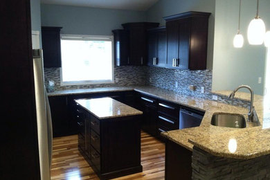 Inspiration for a large galley light wood floor enclosed kitchen remodel in Cedar Rapids with a drop-in sink, flat-panel cabinets, black cabinets, metallic backsplash and an island