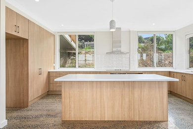 Photo of a mid-sized contemporary galley eat-in kitchen in Melbourne with flat-panel cabinets, white cabinets, quartz benchtops, white splashback, porcelain splashback, concrete floors, with island and white benchtop.