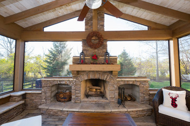 Idée de décoration pour un grand porche d'entrée de maison arrière craftsman avec une cheminée, des pavés en pierre naturelle et une extension de toiture.