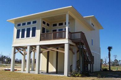 Large beach style yellow two-story wood exterior home photo in Miami with a shingle roof