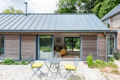 Ejemplo de fachada de casa gris actual de tamaño medio de una planta con revestimiento de madera, tejado a dos aguas, tejado de metal y panel y listón