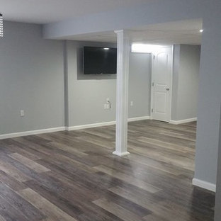 Photo of a large classic fully buried basement in Philadelphia with grey walls, medium hardwood flooring, no fireplace and brown floors.