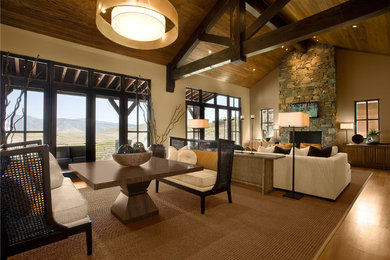 Example of a huge mountain style medium tone wood floor family room design in Salt Lake City with beige walls, a standard fireplace, a stone fireplace and a wall-mounted tv