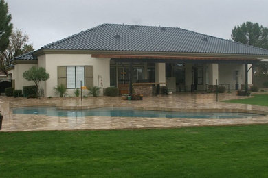 Inspiration for a large traditional backyard custom-shaped pool in Phoenix with natural stone pavers.