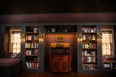 Diseño de sala de estar con biblioteca grande sin televisor con paredes púrpuras