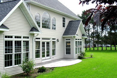 Large elegant white two-story stone exterior home photo in Other with a clipped gable roof