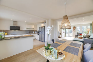 Offenes Modernes Esszimmer mit weißer Wandfarbe, hellem Holzboden und braunem Boden in Düsseldorf