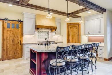 Eat-in kitchen - mid-sized rustic travertine floor eat-in kitchen idea in Orange County with a farmhouse sink, beaded inset cabinets, white cabinets, granite countertops, beige backsplash, stone tile backsplash, stainless steel appliances and an island