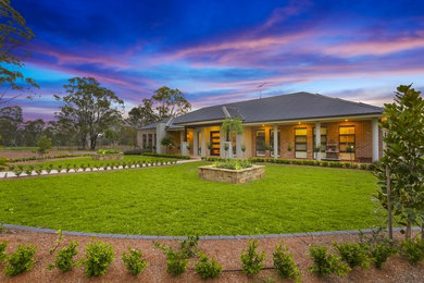 This is an example of a large traditional front yard full sun formal garden for spring in Sydney with a garden path and natural stone pavers.