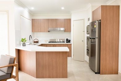 Photo of a contemporary u-shaped eat-in kitchen in Sydney with a drop-in sink, medium wood cabinets, granite benchtops, white splashback, stone slab splashback, stainless steel appliances, ceramic floors, no island and white benchtop.
