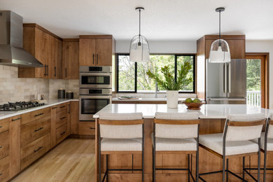 Mid-sized trendy galley medium tone wood floor enclosed kitchen photo in Seattle with an undermount sink, flat-panel cabinets, medium tone wood cabinets, quartz countertops, beige backsplash, subway tile backsplash, stainless steel appliances, an island and white countertops