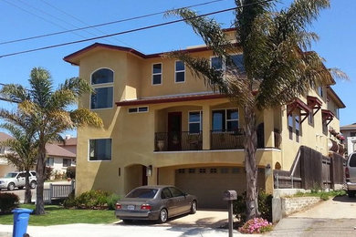 Inspiration for a large timeless yellow three-story stucco exterior home remodel in San Luis Obispo with a mixed material roof