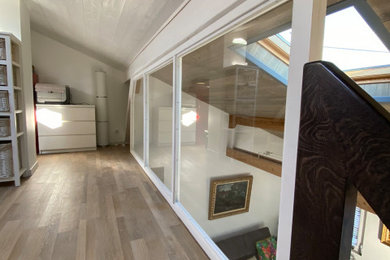 Modelo de dormitorio tipo loft tradicional renovado pequeño sin chimenea con paredes blancas, suelo laminado, suelo marrón y machihembrado