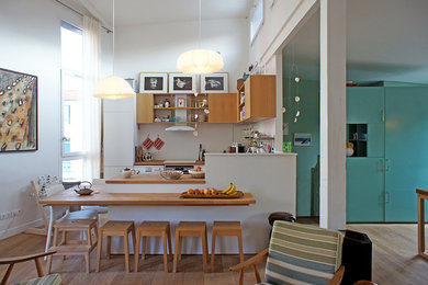 Réalisation d'une grande cuisine américaine design en U avec un évier 2 bacs, des portes de placard blanches, un plan de travail en bois, une crédence blanche, un électroménager en acier inoxydable, parquet clair, un sol marron et un plan de travail marron.